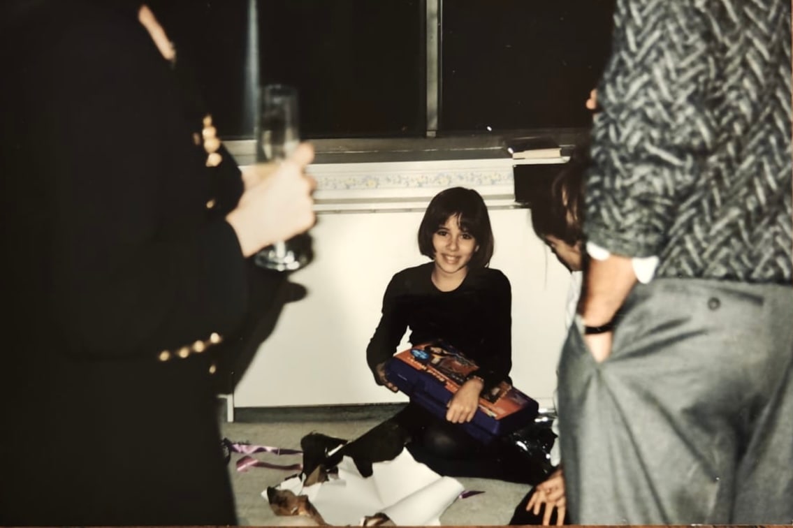 Daniela, around ten to twelve years old, sits on the floor among adults.